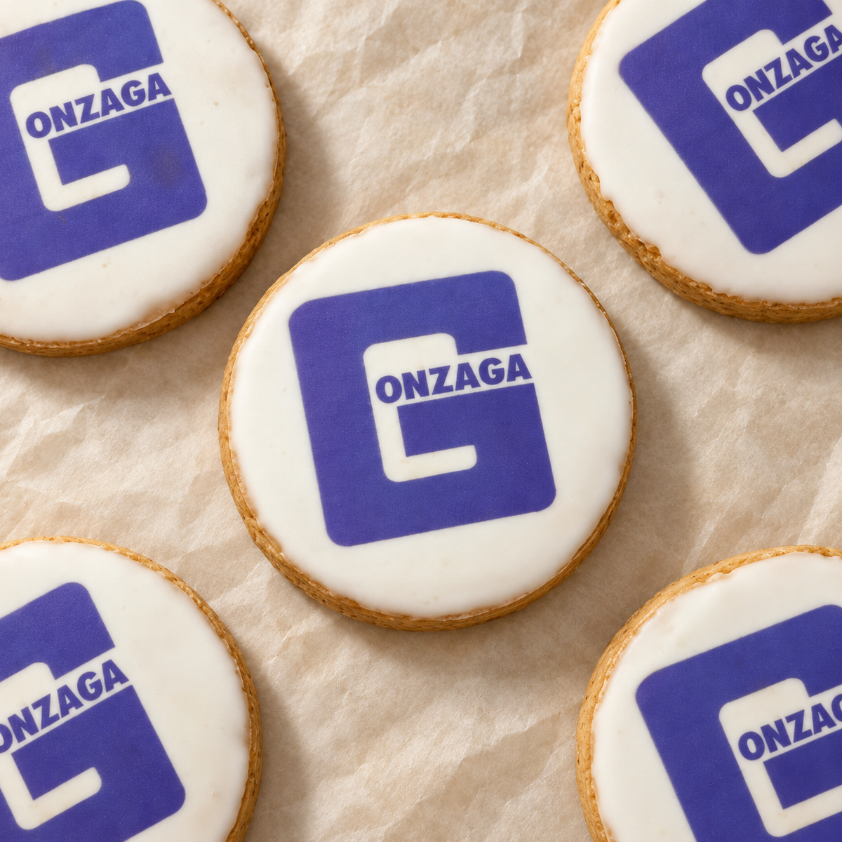 Gonzaga-logo cookies arranged on cream parchment